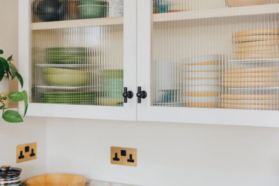 A bespoke kitchen wall cupboard with glass doors made with fluted glass.