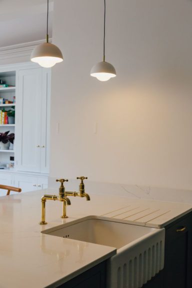 Marble kitchen worktop with a Belfast sink and drainer grooves, it has overhead pendant lighting.