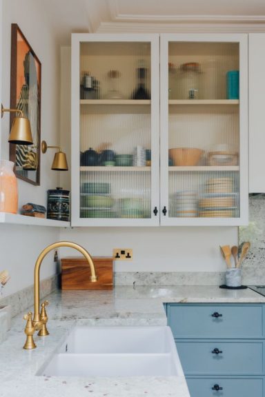 Glazed kitchen wall cabinet with reeded glass above painted drawers with custom fronts.