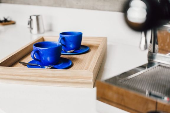 Handmade oak tea tray with blue cups on it, made in Sheffield. Bespoke furniture design.
