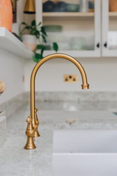 Natural stone kitchen worktops with exquisite grain fitted with brass taps.