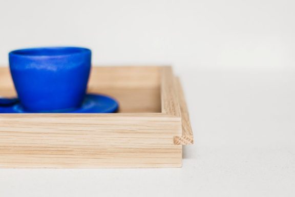Handmade oak tea tray with blue cups on it, made in Sheffield. Bespoke furniture design.